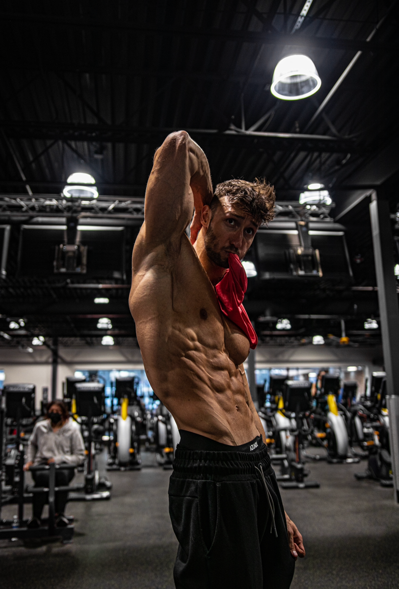 Coach is posing showing his muscles in the gym.